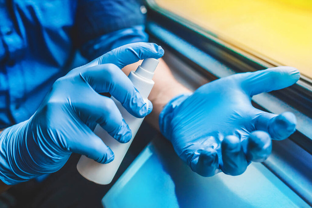 Businessman hands in protective medical gloves hold and spray antiseptic, soft focus - Foto, afbeelding