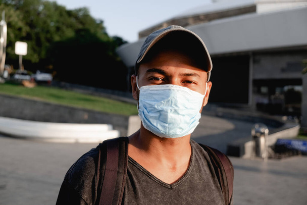 Şehir caddesinde yüzünde tıbbi koruyucu maske olan genç Afrikalı bir adamın portresi. Koronavirüs salgınının önleyici tedbirler ve korunması kavramı. - Fotoğraf, Görsel