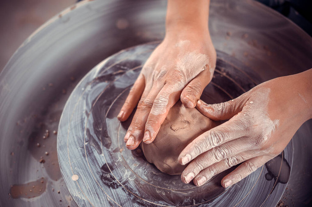 Il maestro-ceramista crea una pentola di argilla su una ruota di vasai. Mani di vasaio da vicino. Artigianato antico e ceramica lavoro fatto a mano - Foto, immagini
