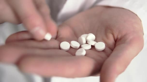 Un médecin compte des pilules blanches sur sa main en gros plan - Séquence, vidéo