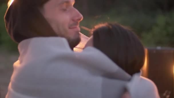 Close-up van gelukkig jong stel opwarmen met dekens op openluchtfeest en man zoenen vriendin in voorhoofd romantisch op zomeravond - Video
