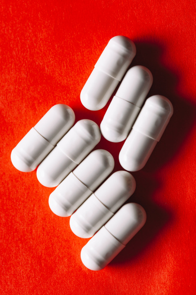 Таблетки в белых капсулах в красном. Таблетки для лечения заболеваний желудка - Фото, изображение