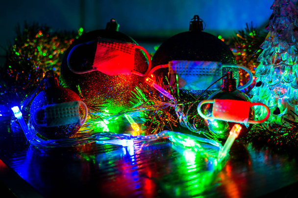 A family of Christmas balls in protective masks from the pandemic. New Year and Christmas in quarantine, in self-isolation due to the global coronavirus pandemic. - Foto, afbeelding