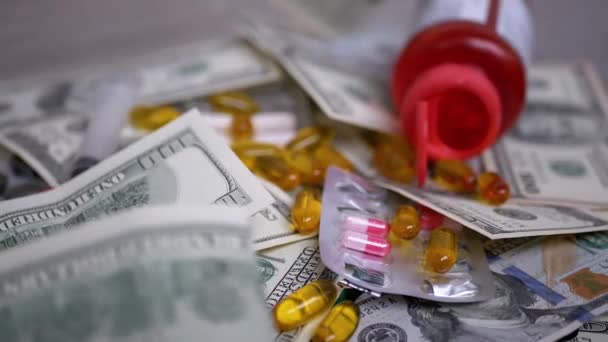Paquete de billetes de dólar cae en la mesa con dinero, píldoras. Aumento de los costes sanitarios - Metraje, vídeo