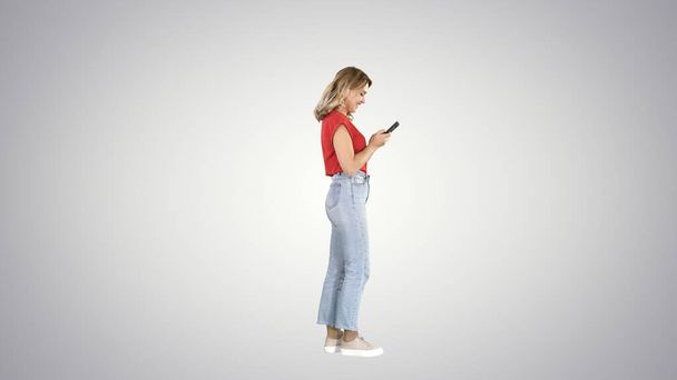 Casual young woman typing on mobile phone on gradient background - Foto, Bild