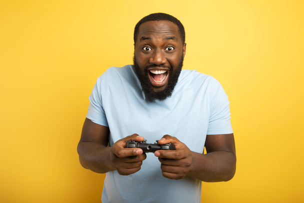Uomo felice gioca con un videogioco su sfondo giallo - Foto, immagini