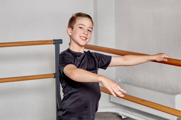 A handsome guy in the gym trains ballet. Training in ballet and gymnastics. - Zdjęcie, obraz