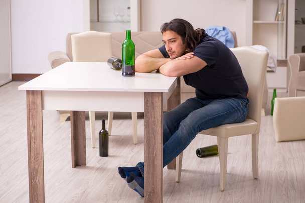 Fiatal munkanélküli férfi, aki otthon iszik alkoholt - Fotó, kép