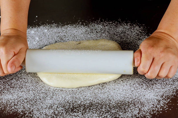 Rodillo en mano de mujer y pasta de azúcar blanca en la mesa. - Foto, Imagen