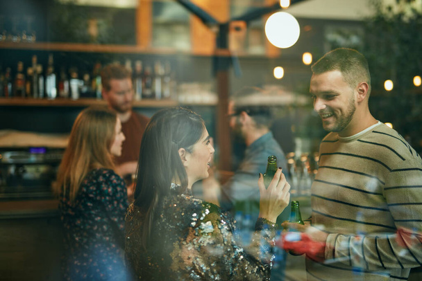 Grupo de personas de pie en un bar, charlando y bebiendo cerveza. - Foto, Imagen