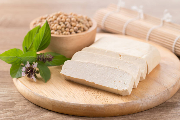 Sliced tofu and soybean seeds on wooden cutting board prepare for cooking, Asian vegan food - Photo, Image