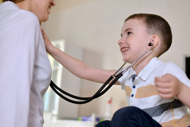 The child is at the pediatrician appointment. He listening to a stethoscope. They look into each other eyes. - Foto, Imagem