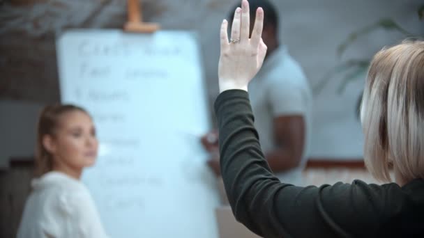 Lekcja angielskiego w klasie z czarnym nauczycielem - dwie kobiety siedzące przy stole i jedna z nich podnosi rękę i wychodzi z klasy - Materiał filmowy, wideo