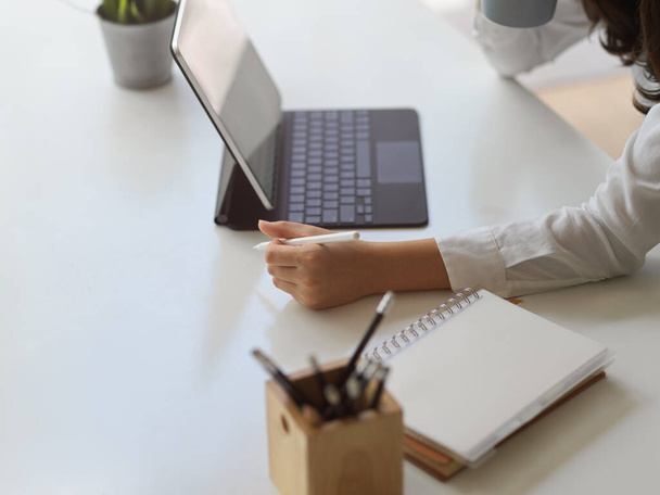 Widok boczny dłoni kobiet pracujących z tabletem cyfrowym i notebookiem na białym stole - Zdjęcie, obraz