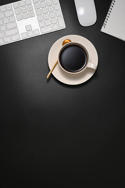 Vista dall'alto dell'area di lavoro con tazza da caffè, tastiera, mouse e spazio copia sul tavolo nero - Foto, immagini