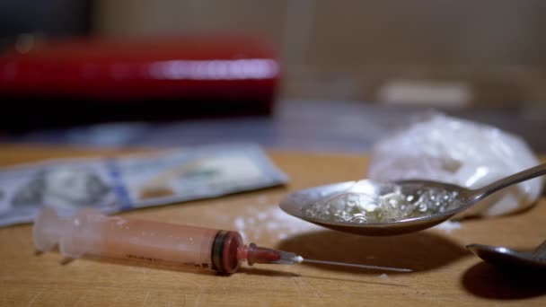 Hand Addict cocina heroína en cuchara en casa, contra el telón de fondo Jeringa usada - Metraje, vídeo