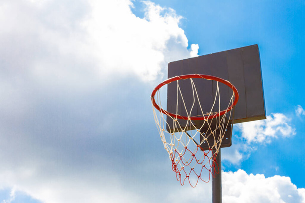 Відкритий баскетбольний кільце з блакитним небом і хмарами фону
 - Фото, зображення