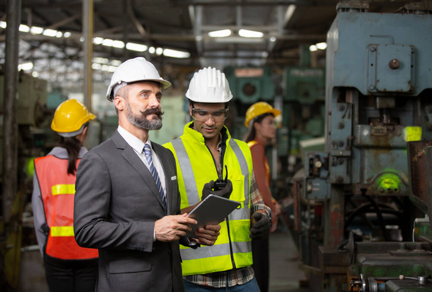 Mužští průmysloví inženýři mluví s továrním dělníkem. Pracují ve výrobním závodě těžkého průmyslu. - Fotografie, Obrázek