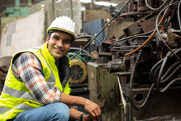 Ingenieros operando una máquina cnc en fábrica, Retrato del trabajador sonriente presionando botones en el panel de control electrónico y mirando a la cámara mientras opera unidades de la máquina en la fábrica moderna - Foto, Imagen