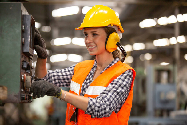 Retrato del trabajador sonriente pulsando botones en el panel de control electrónico y mirando a la cámara mientras opera unidades de máquinas en la fábrica moderna, Ingenieros femeninas que operan una máquina CNC en fábrica - Foto, imagen