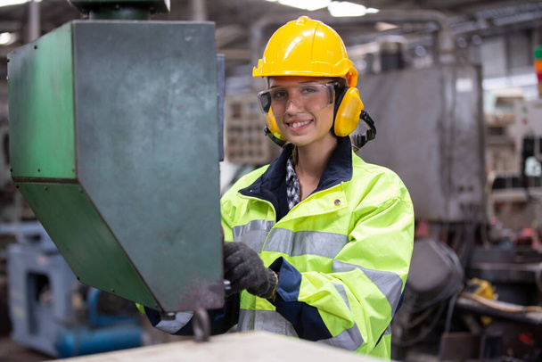 Retrato del trabajador sonriente pulsando botones en el panel de control electrónico y mirando a la cámara mientras opera unidades de máquinas en la fábrica moderna, Ingenieros femeninas que operan una máquina CNC en fábrica - Foto, imagen