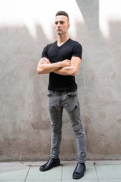 Full length shot of handsome young Italian man with undercut standing with arms crossed - Foto, immagini