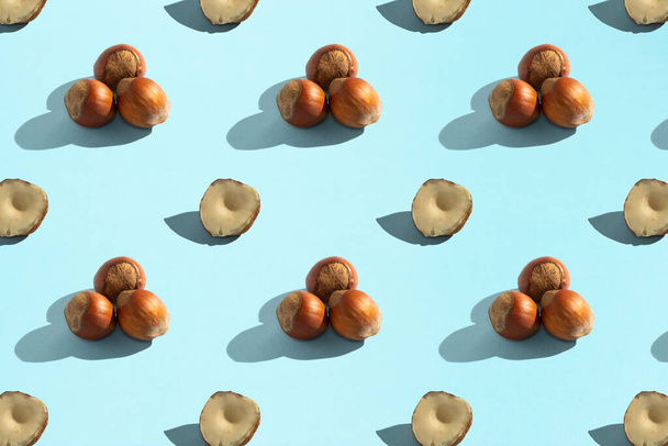 Hazelnuts on a blue background, seamless pattern, hard shadows. Healthy vegetarian food, background for design. - Foto, Imagen