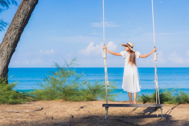 Ritratto bella giovane donna asiatica rilassarsi sorriso su swing intorno spiaggia mare oceano per natura viaggiare in vacanza - Foto, immagini