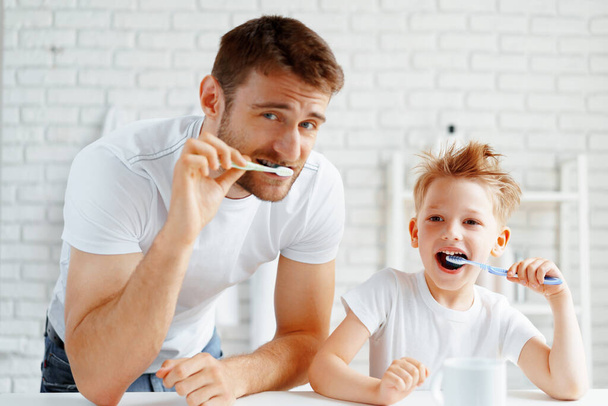 Dad and little son brushing teeth together - Фото, зображення