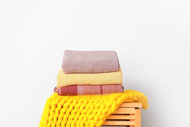 Chest with knitted plaids on light background - Foto, Imagen