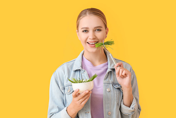 Young woman eating wheatgrass on color background - Photo, Image