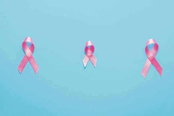 Pink ribbons on color background. Breast cancer awareness concept - 写真・画像