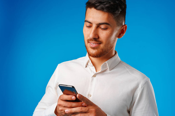 Giovane uomo in camicia bianca con il suo smartphone - Foto, immagini