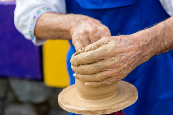 An elderly man makes a jug out of clay, close-up - Foto, afbeelding