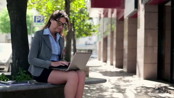 Businesswoman working on laptop in city - Кадры, видео