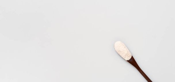 Collageen eiwit poeder in een plastic maatlepel op een witte achtergrond, plat gelegd. Aanvullende eiwitsuppletie voor de gezondheid van lichaam en gewricht. Op een natuurlijke basis. Ruimte voor tekst - Foto, afbeelding