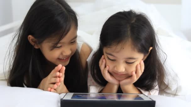 Little Asian girls play tablet on the bed - Footage, Video