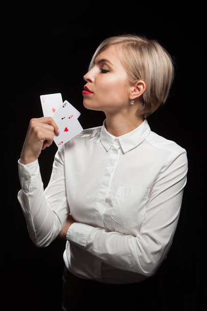 Belle femme blonde montrant une carte de poker sur fond noir - Photo, image