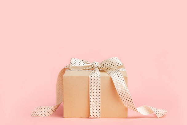 craft box gift with ribbon bow on pastel pink background with place for text. copy space card - 写真・画像