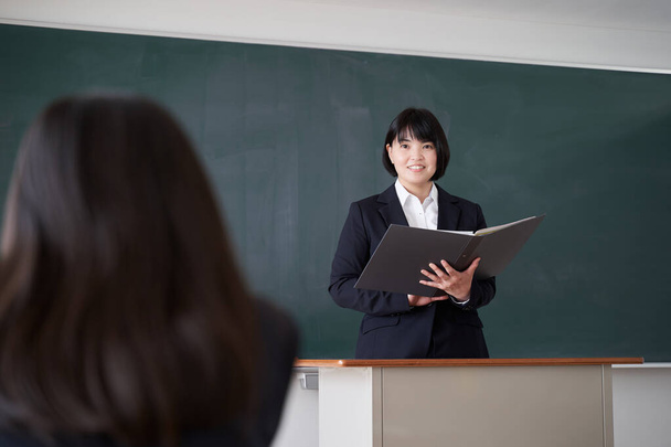 日本の女性教師が教室で生徒に尋ねる - 写真・画像