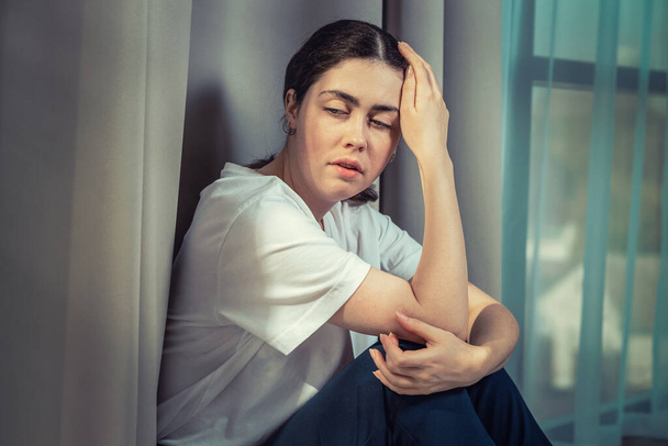 Porträt einer frustrierten Frau, die ihren Kopf mit der Hand hält. Dunkle Farben. Das Konzept der häuslichen Gewalt. - Foto, Bild