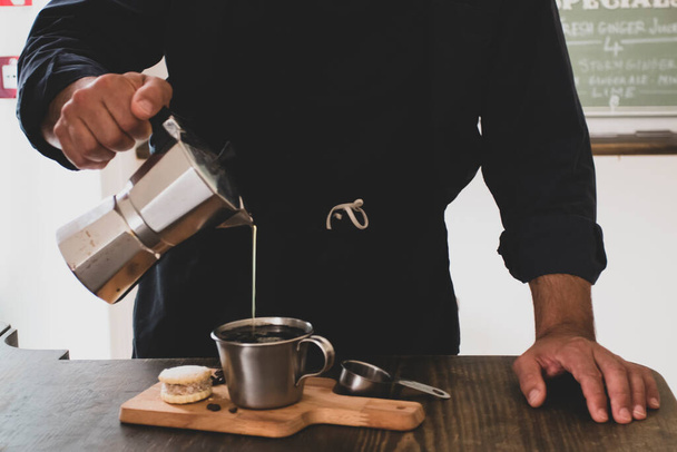 Erkek Barista süslü bir kahve dükkanında müşteriler için kahve makinesinde taze espresso hazırlıyor. Kahve dükkanında müşteriye servis yapan bir kafe sahibi.. - Fotoğraf, Görsel