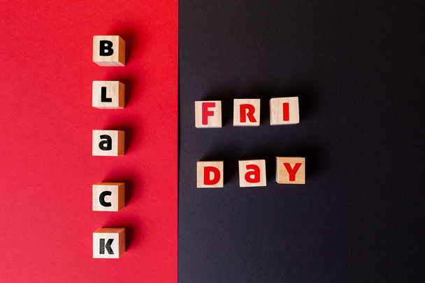 Concept of holidays sales. On a red and black background are wooden cubes with the inscription black Friday. Flat lay. Copy space. Close up. - Photo, Image