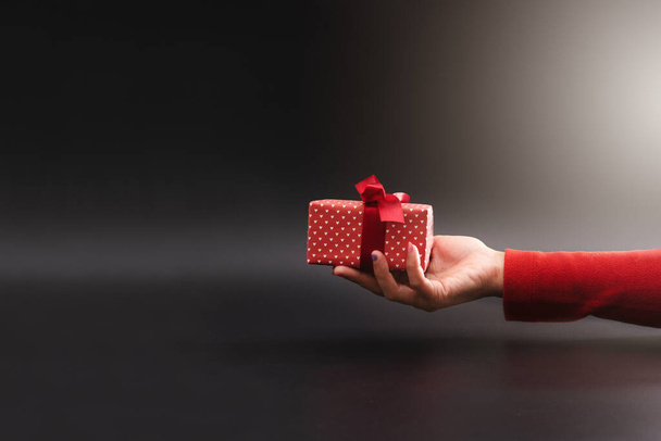 Nainen käsi antaa lahjan mustalla taustalla, Joulun Nyrkkeilypäivä käsite - Valokuva, kuva