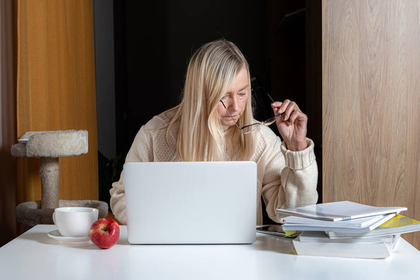 middle aged businesswoman sitting at desk working with documents and laptop from home office - Foto, Imagen
