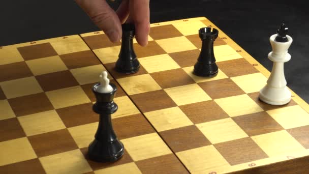 Guy fekete figurák tesz egy lineáris szőnyeg két bástya a fehér király, és ő esik a sakktáblára - Felvétel, videó