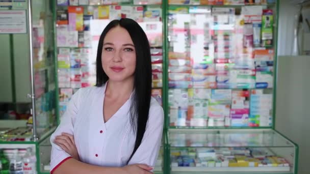 Een mooie brunette vrouw werkt als apotheker, poseren tegen de achtergrond van een apotheek venster. - Video