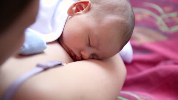 A kisfiú kint alszik az anyák mellkasán. anya átöleli alvó baba karjaiban és megcsókolja a gyereket gyengéden - Felvétel, videó