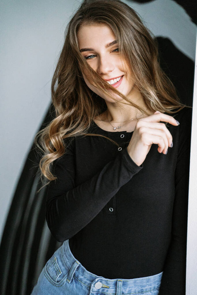 Portrait of a beautiful girl with blond long hair in a black T-shirt and jeans - Foto, immagini