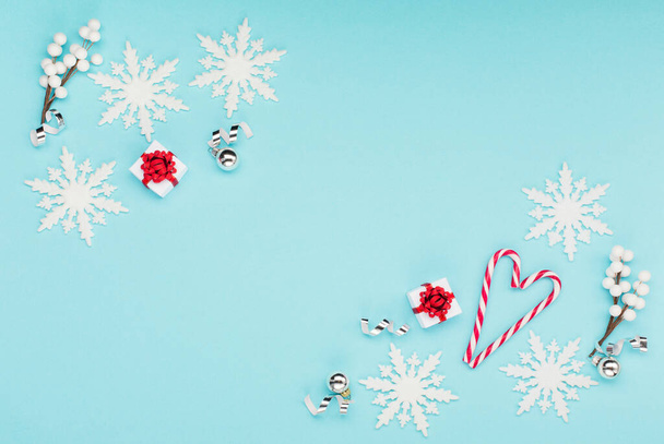 Noël vacances hiver Nouvel An carte de fête. Coffrets cadeaux rouges de Noël, flocons de neige, cannes à bonbons sur fond bleu pastel. Pose plate, vue du dessus, espace de copie. - Photo, image